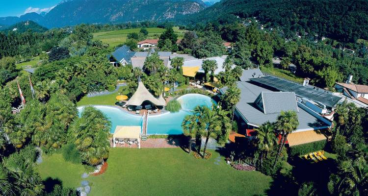 Aerial view of a resort with pools and palm trees in a mountainous area.