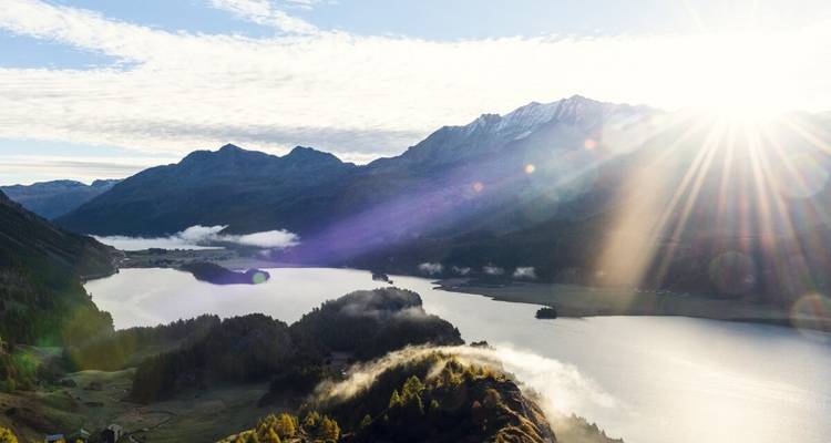 Vue panoramique de lacs et de montagnes sous un soleil éclatant.