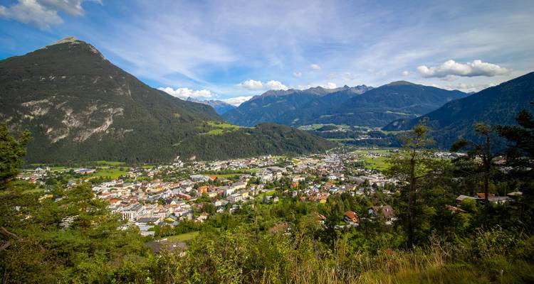 Vue panoramique d'une ville de montagne entourée de vallées vertes et de montagnes.