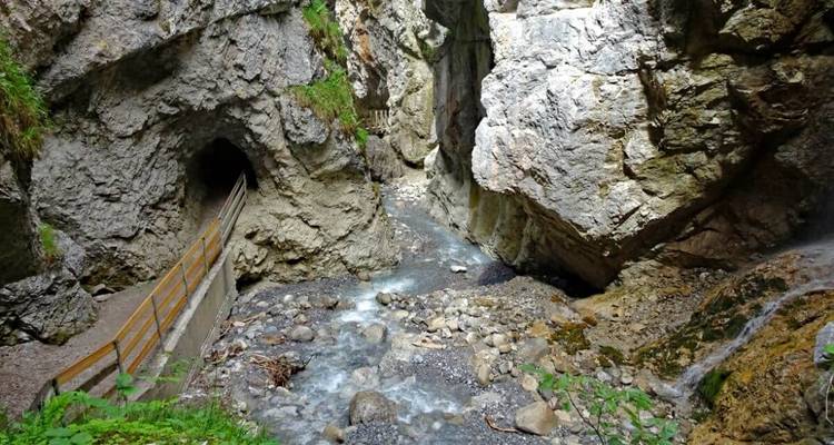 Rivière étroite traversant une gorge rocheuse avec un sentier en bois.