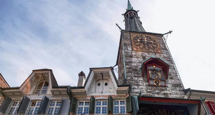 Tour d'horloge sur un bâtiment historique orné sous un ciel bleu.