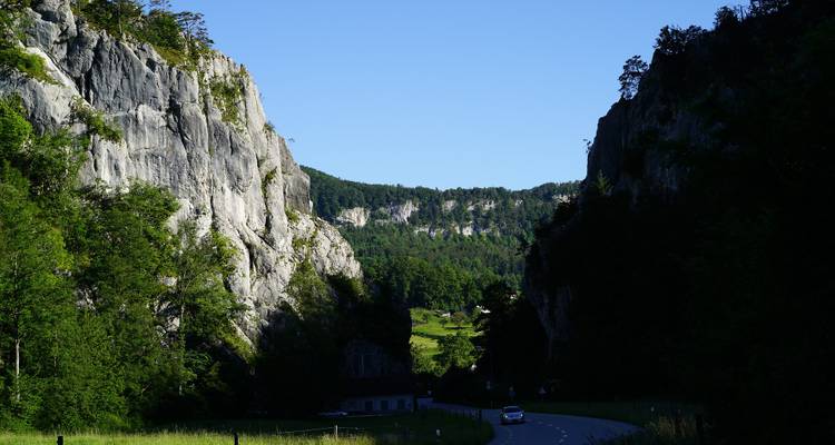 Une route serpentant à travers une vallée avec d'imposantes falaises rocheuses.
