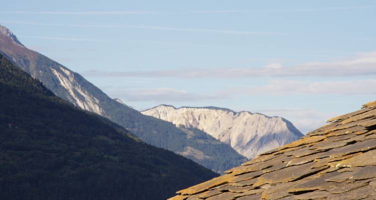 Partial mountain view with the edge of a roof in foreground.