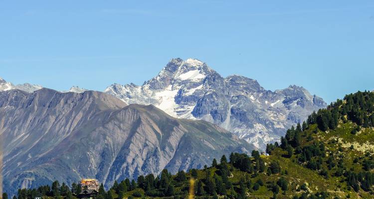 Majestic mountain peak with clear sky and trees in foreground.