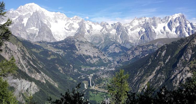 Panoramic view of a valley with a town and surrounding snow-capped mountains.