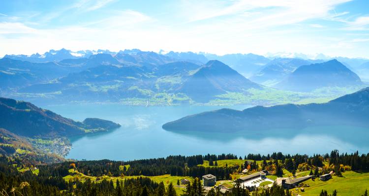 Vue étendue d'un lac et de montagnes depuis un point de vue élevé.
