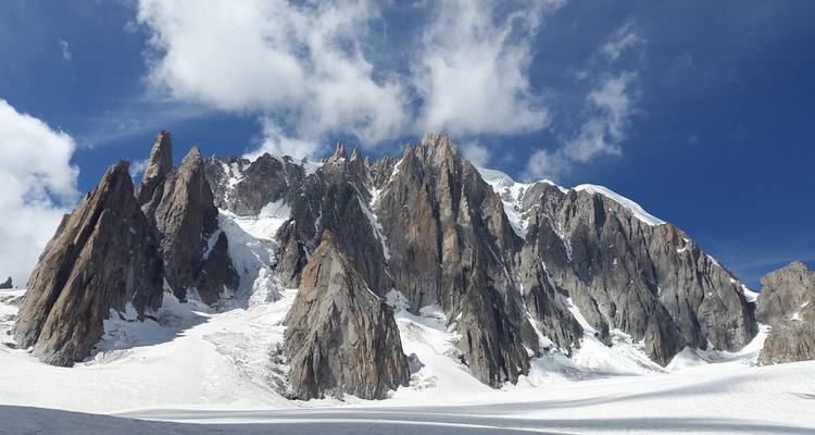Picos montañosos nevados bajo un cielo azul con nubes.