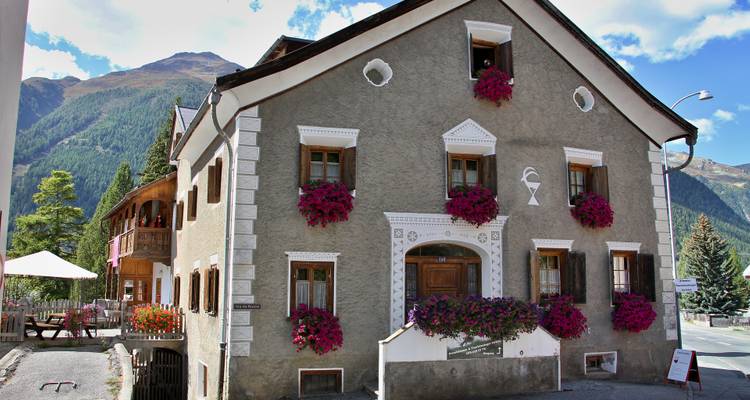 Maison traditionnelle couverte de fleurs avec des montagnes en arrière-plan.