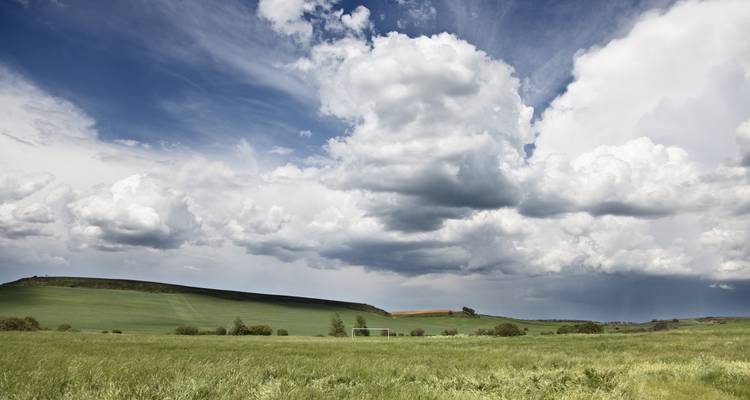 Vast green landscape with dramatic clouds in the sky.