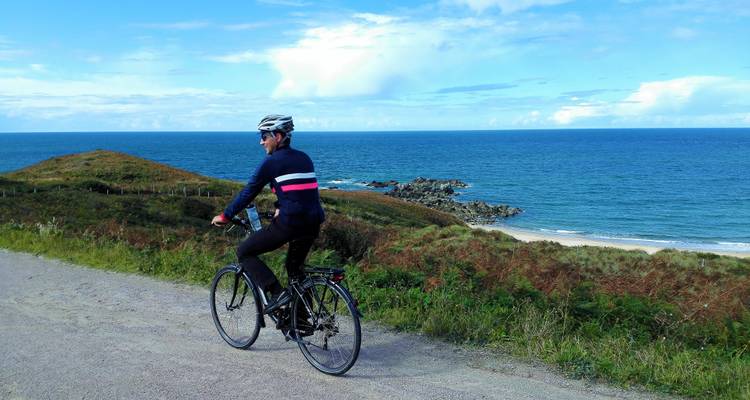 A man cycling on a coastal path with an ocean view.