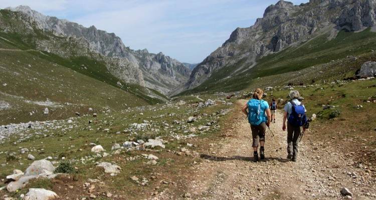 Des randonneurs marchant le long d'un sentier de montagne au terrain rocheux.