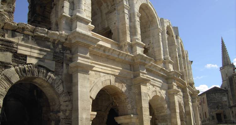 Amphithéâtre romain antique avec des arches de pierre et un ciel dégagé.