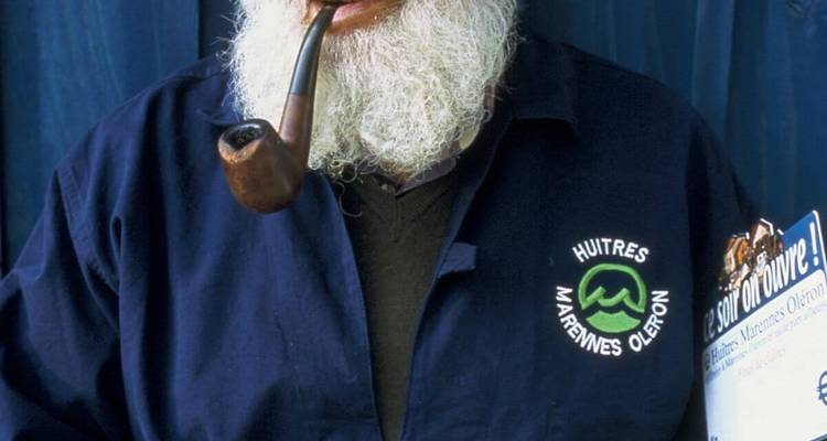 Personne avec une barbe portant une chemise avec un logo et une pipe.