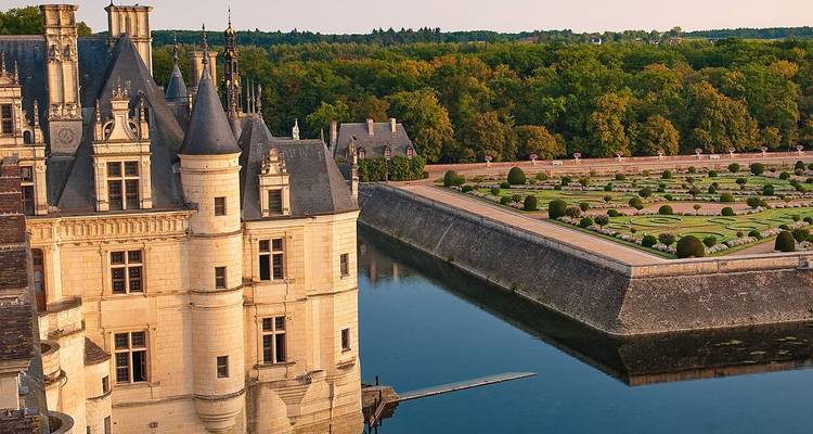 Château élégant avec jardins à la française et douves.