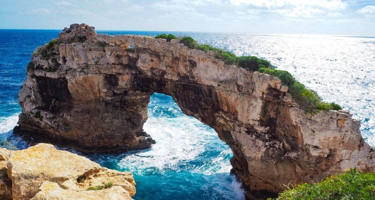 Une arche de pierre naturelle au-dessus de la mer avec des vagues qui se brisent en contrebas.