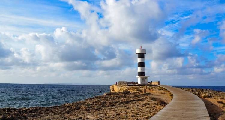 Un phare rayé noir et blanc au bord de la mer avec une promenade en planches.