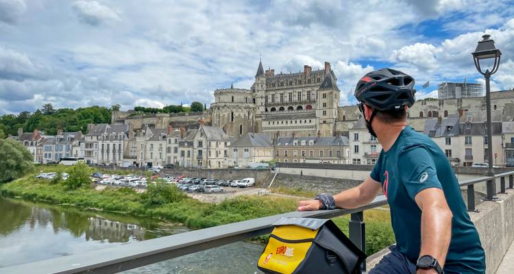 Le cycliste s'arrête sur le pont pour admirer l'impressionnant château de l'autre côté de la rivière