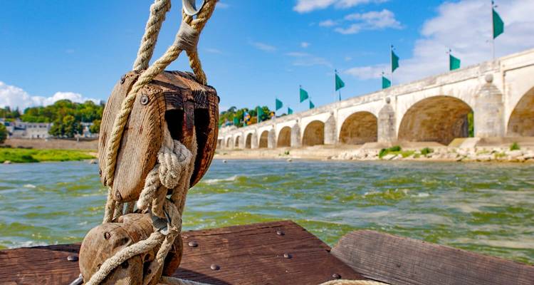 Vue d'un pont de pierre depuis un bateau sur une rivière.
