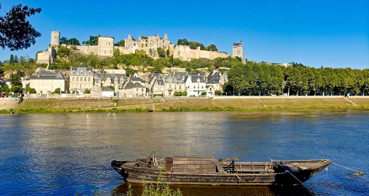 Forteresse historique au bord d'une rivière avec un petit bateau.