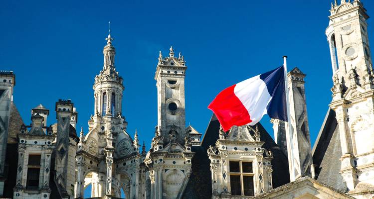 Gros plan du drapeau français avec un bâtiment historique.