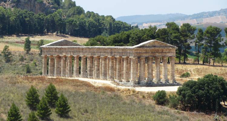 Temple antique en pierre dans un cadre champêtre.