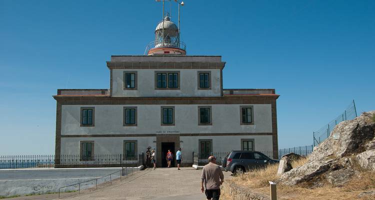 Ein Leuchtturm auf einer kleinen Halbinsel mit Menschen, die zum Eingang gehen.