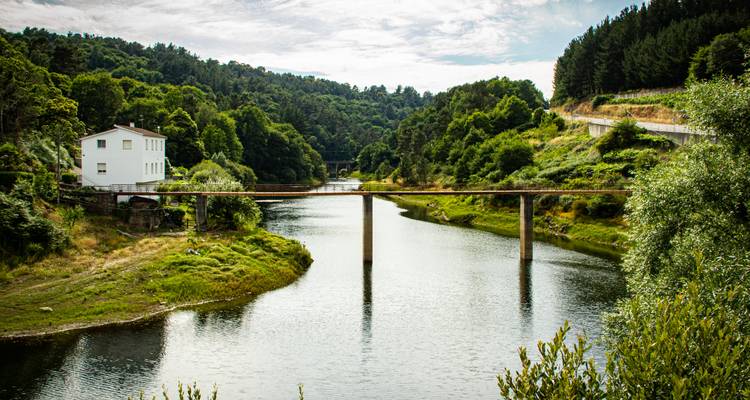A river with a bridge surrounded by lush green hills.