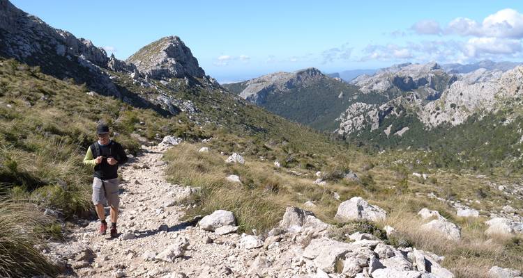 Randonneur sur un sentier de montagne rocheux avec des vues panoramiques.