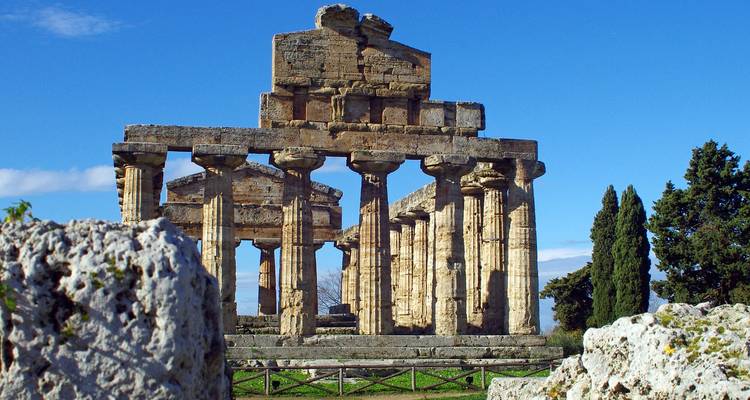 Gut erhaltene dorische Tempelruinen von Paestum unter klarem blauen Himmel.