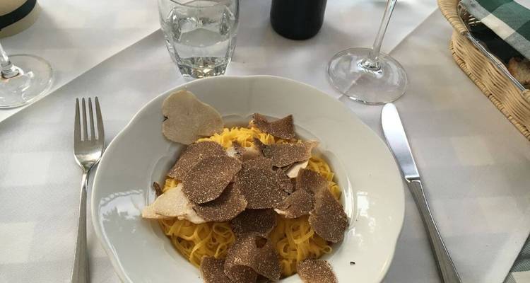 Assiette de pâtes garnie de truffes dans un cadre de restauration en plein air.
