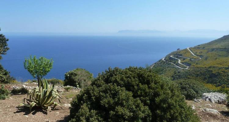 Vue panoramique d'une route côtière et de la mer au loin sous un ciel dégagé.