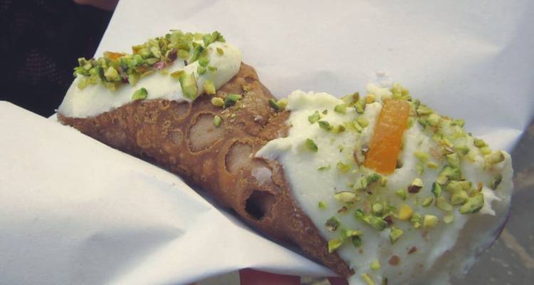 Gros plan d'un cannoli aux pistaches et quartiers d'orange.