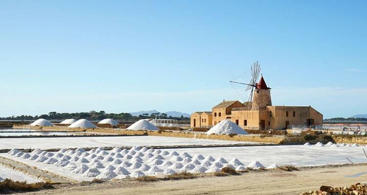 Moulin à vent historique et marais salants avec des monticules de sel blanc.