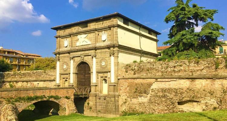Historische poort en oude muur onder een blauwe hemel.