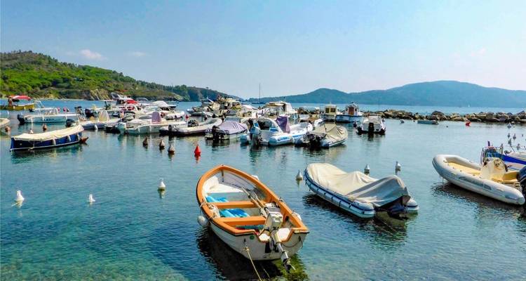 Boote liegen in einem kleinen Hafen vor Anker mit Bergen in der Ferne.