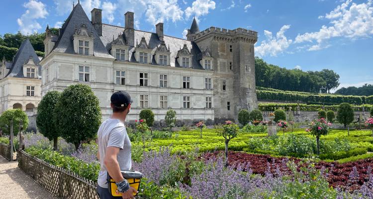 Homme avec casque de vélo admire les jardins colorés du château en fleurs d'été