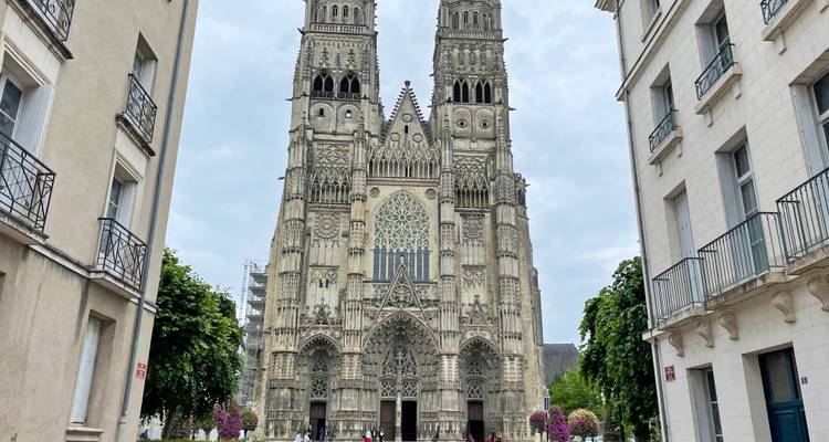 Cathédrale gothique avec tours jumelles encadrée par des bâtiments urbains