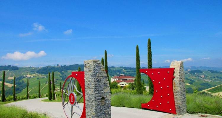 Installation d'art moderne devant des collines ondulantes avec des cyprès.