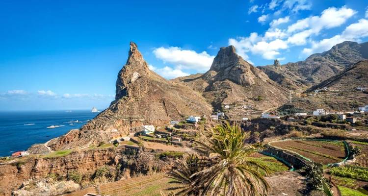 Vue aérienne d'un village côtier avec des collines escarpées.