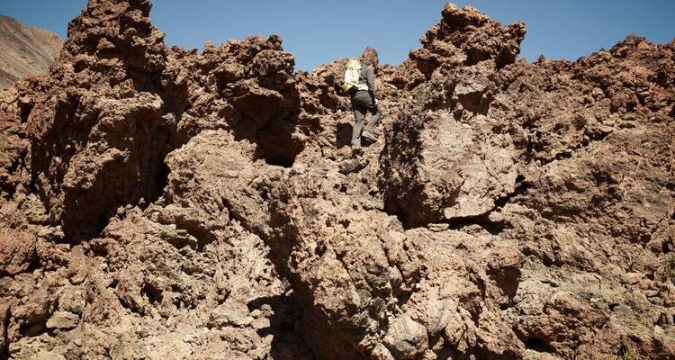 Personne escaladant sur un terrain rocheux et accidenté.