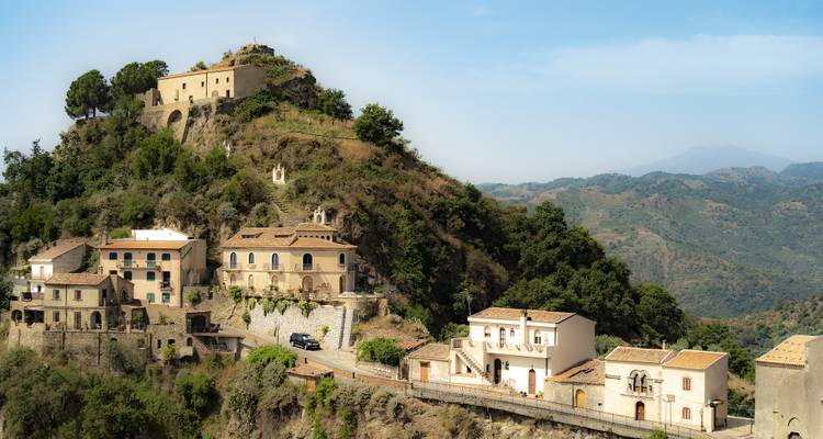 Maisons sur une colline escarpée avec un décor montagneux en arrière-plan.