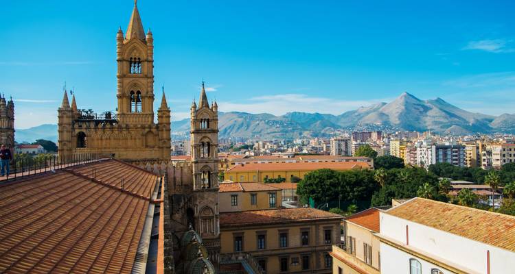 Vue panoramique d'une ville avec des bâtiments historiques et une chaîne de montagnes.