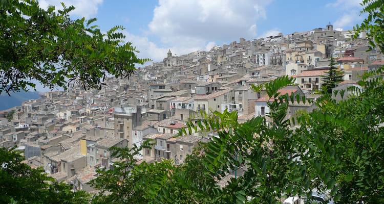 Une ville historique densément peuplée sur une colline sous un ciel partiellement nuageux.