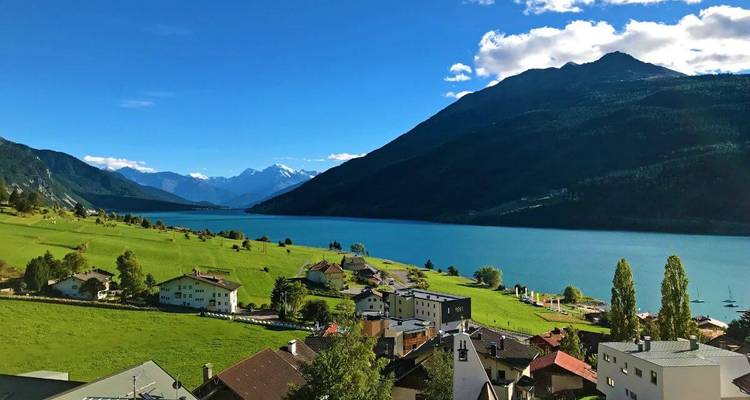 Lakeside view with mountains and village.