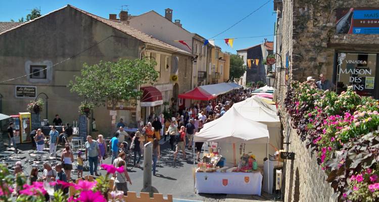 Marché de rue avec des tentes et des gens dans un cadre villageois.