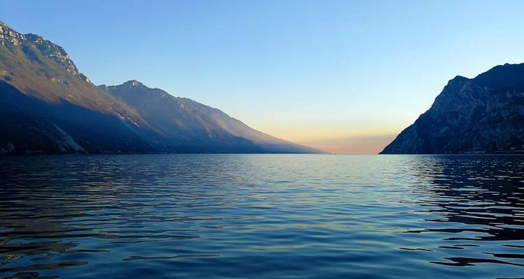 Lac entouré de montagnes au coucher du soleil.