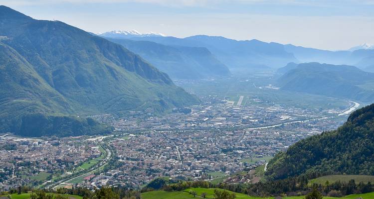 Vue aérienne d'une vallée entourée de montagnes avec une ville.