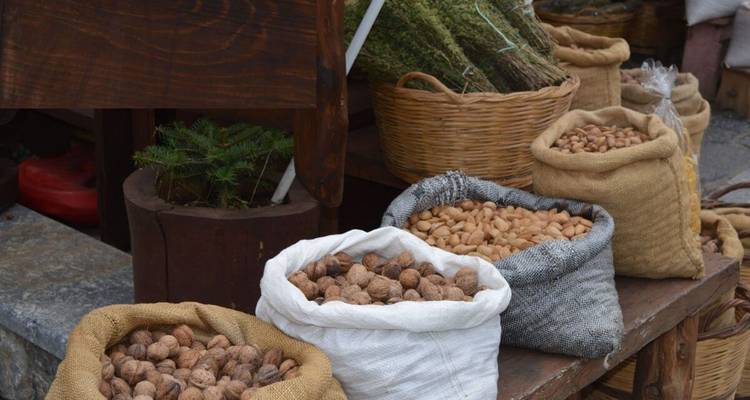 Des sacs de diverses noix et herbes exposés dans un cadre de marché.