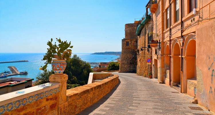 Küstenstadt-Straße mit Meerblick und historischen Gebäuden.