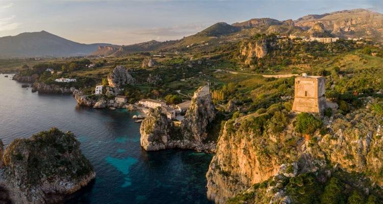 Küstenlandschaft mit Felsklippen und historischem Turm.